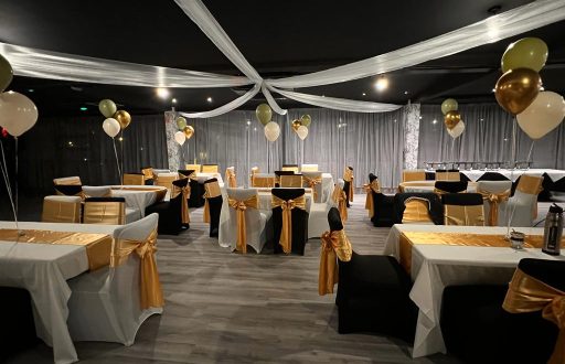 white and gold theme, nicely decorated, gold ribbons on the back of black cloth chairs