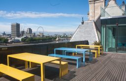 yellow and blue tables and benches, view of the London Eye
