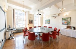 meeting room, round table, red chairs, water bottle and glasses, natural lighting