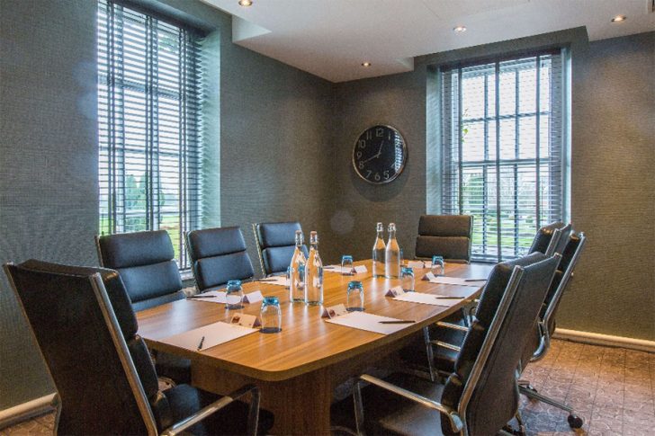 small meeting space, comfortable black chairs, windows, clock