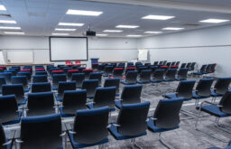 conference room, projector screen, lit room, theatre style, flip chart, lecturn