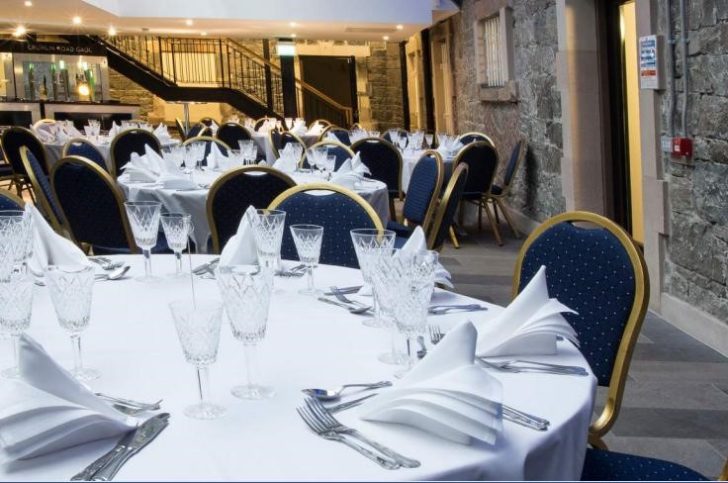 nicely decrocrative napkins, fine glasses, cutlery, brick walls, stairs, tables, blue chairs