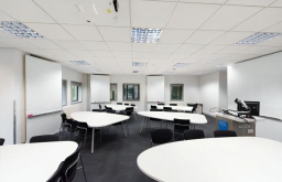 three large whiteboards,conference layout, white tables and black chairs