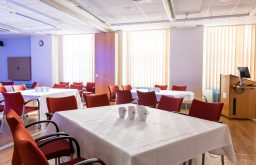 white covered tables, conference room, natural lighting, cups on the tables