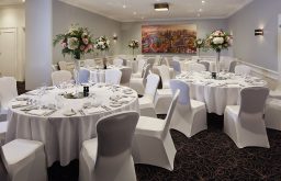 painting on the wall, gala dinner, white covered chairs and tables