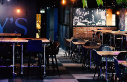 bar, wooden tables, leather chairs, bar stools, dimly lit event space
