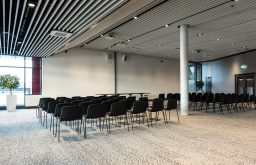chairs set out in theatre, head table in the front, l;arge conference room, modern venue