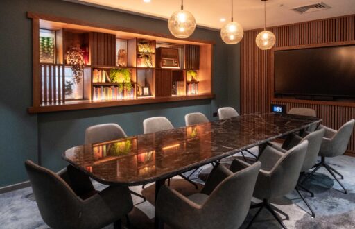 Large TV screen, modern meeting room, boardroom layout, inspiring event space, lit bookshelves, comfortable meeting chairs