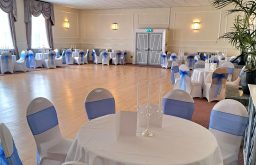 blue ribbon behind white covered chairs, cabaret tables, natural day lighting