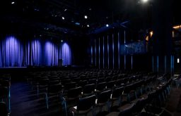 theatre set up, stage with curtains, comfortable black chairs