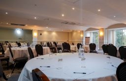 cabaret layout, flip chart, water bottles anf glasses on the table, conference room